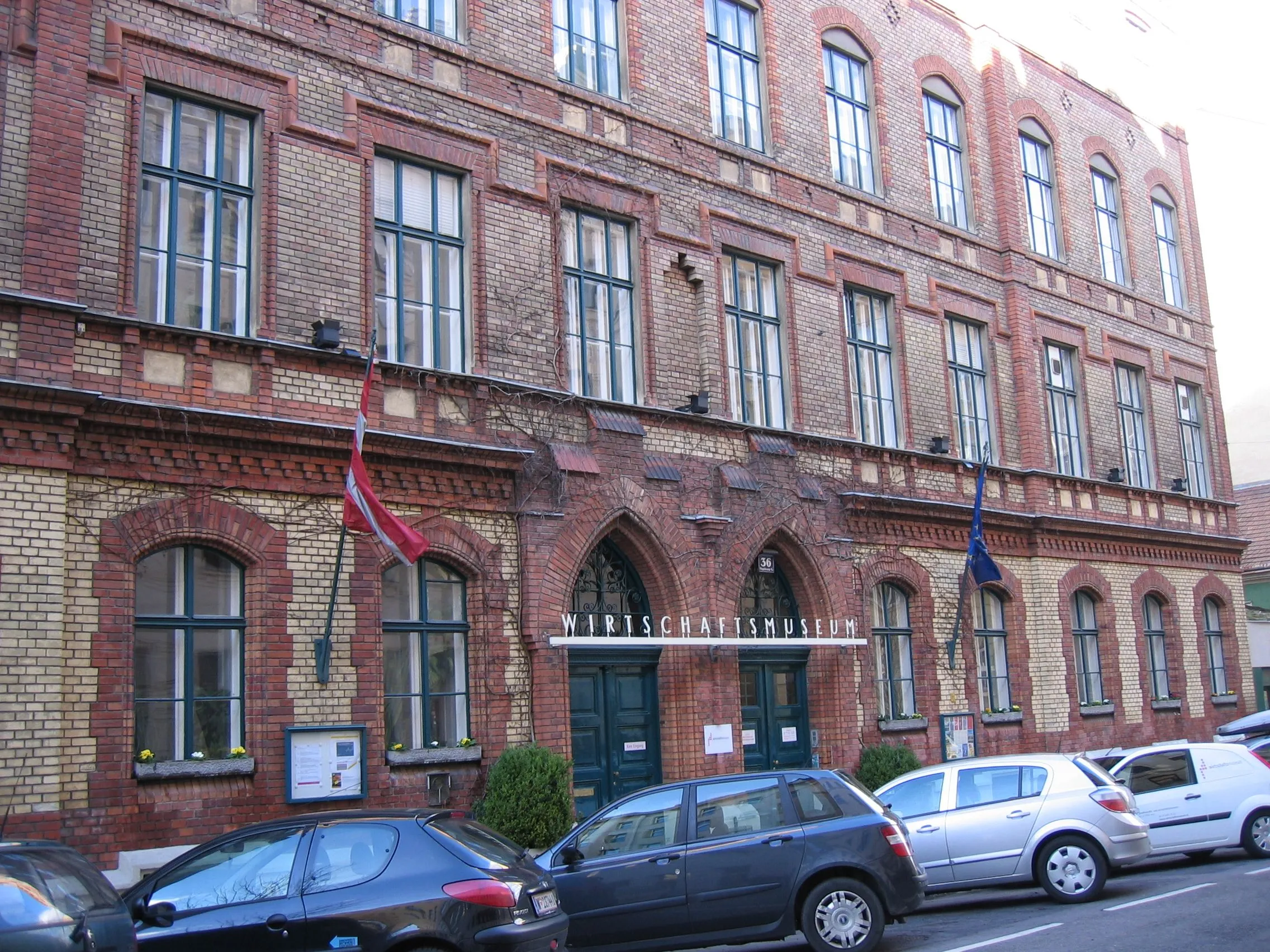 Rood bakstenen gebouw met boogramen en ingang, bord met de tekst Wiener Wirtschaftsmuseum
