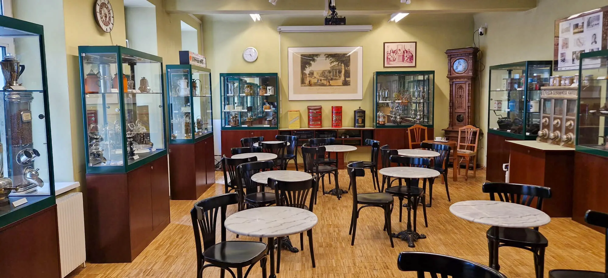 Interieur van het Koffiemuseum met vitrines, tafels, stoelen en ingelijste foto's aan de muren