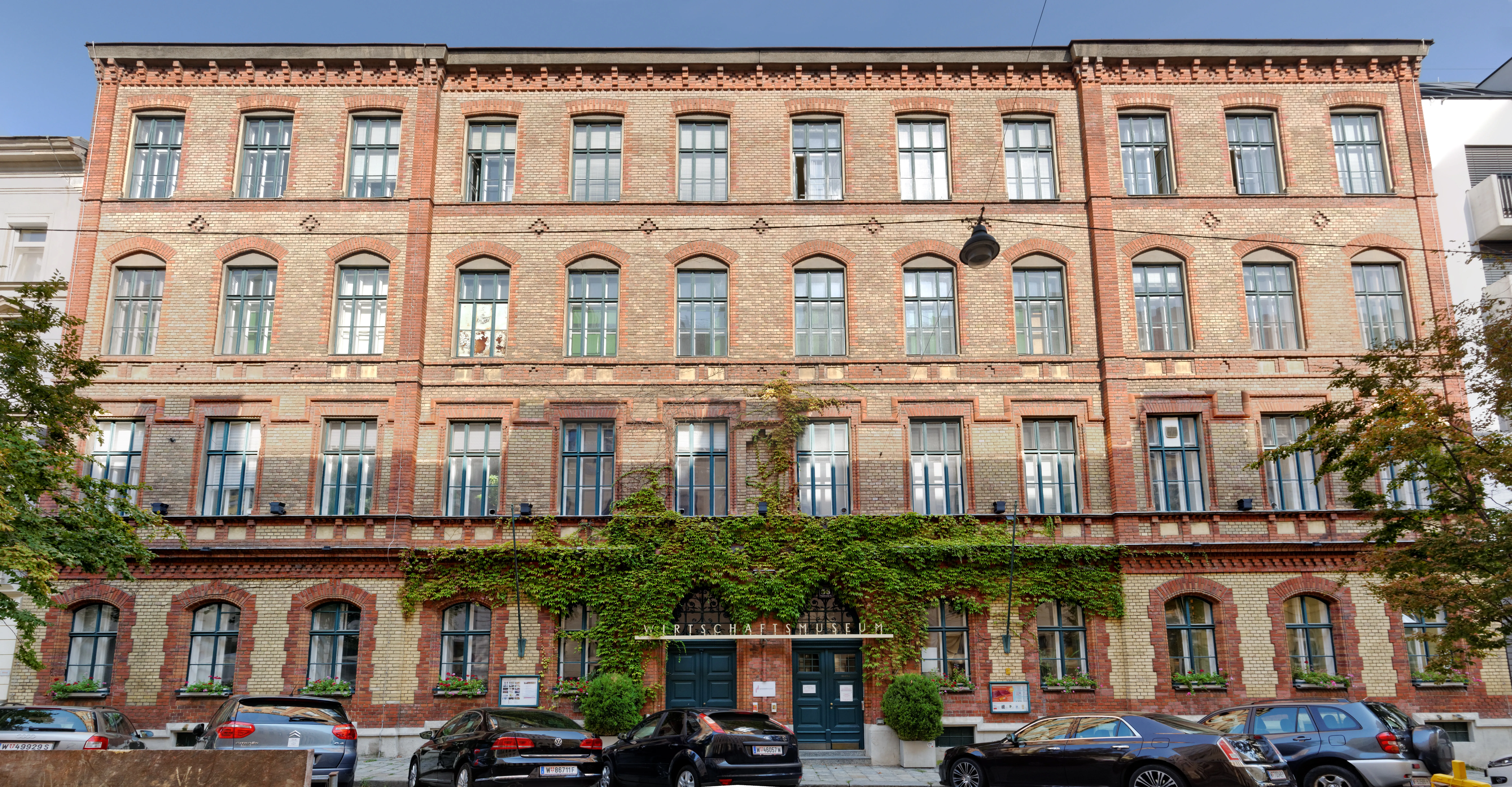 Een meerlaags roodstenen gebouw met boogramen en klimop op de gevel, geïdentificeerd als het Koffiemuseum.
