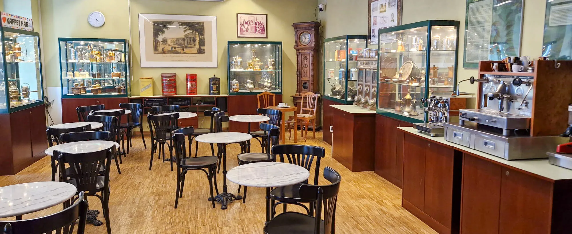 interieur van een koffiemuseum met tafels, stoelen en glazen vitrines