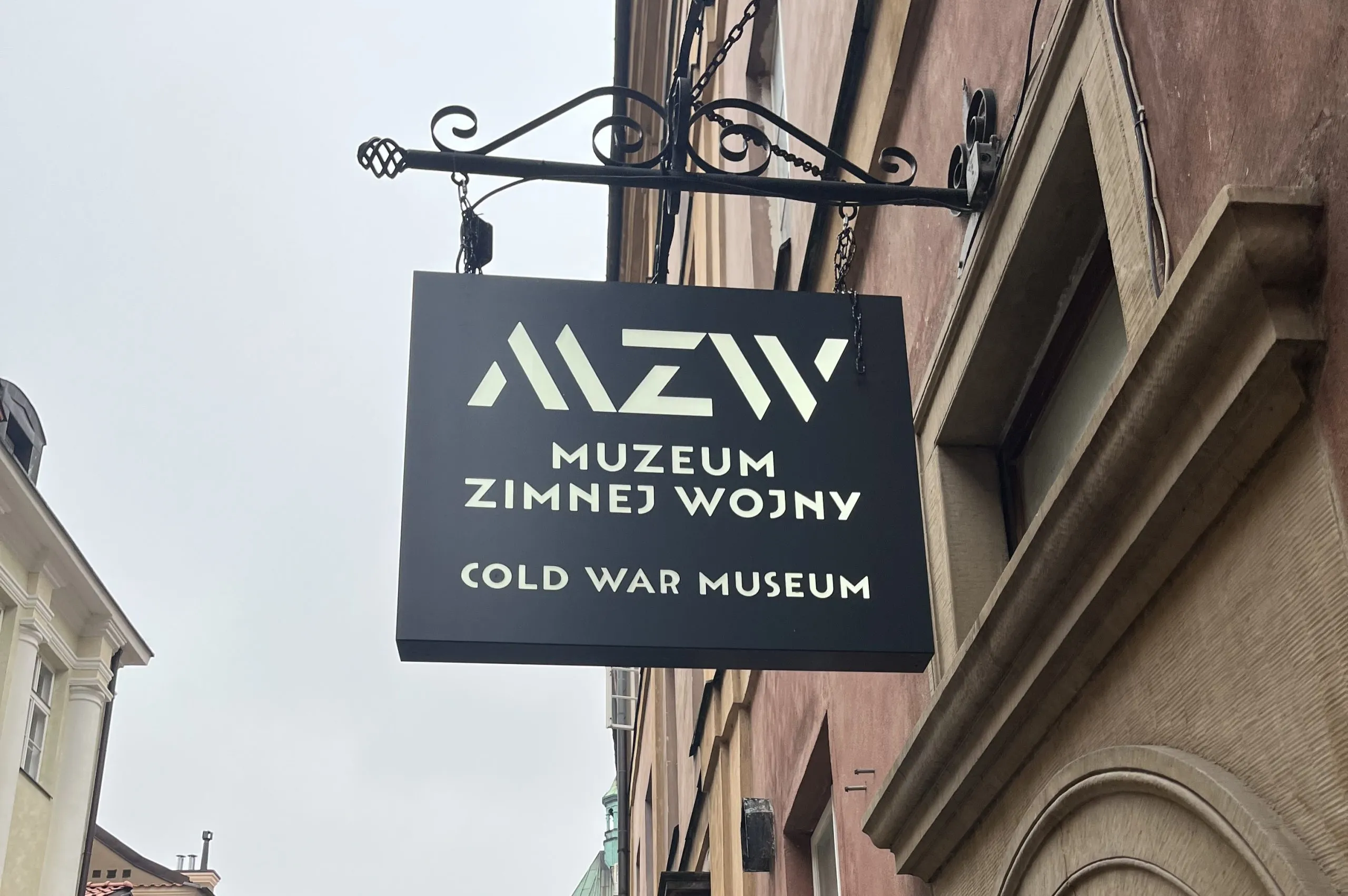 Cartel negro con texto blanco 'MZWW MUZEUM ZIMNEJ WOJNY COLD WAR MUSEUM' colgado en la fachada de un edificio