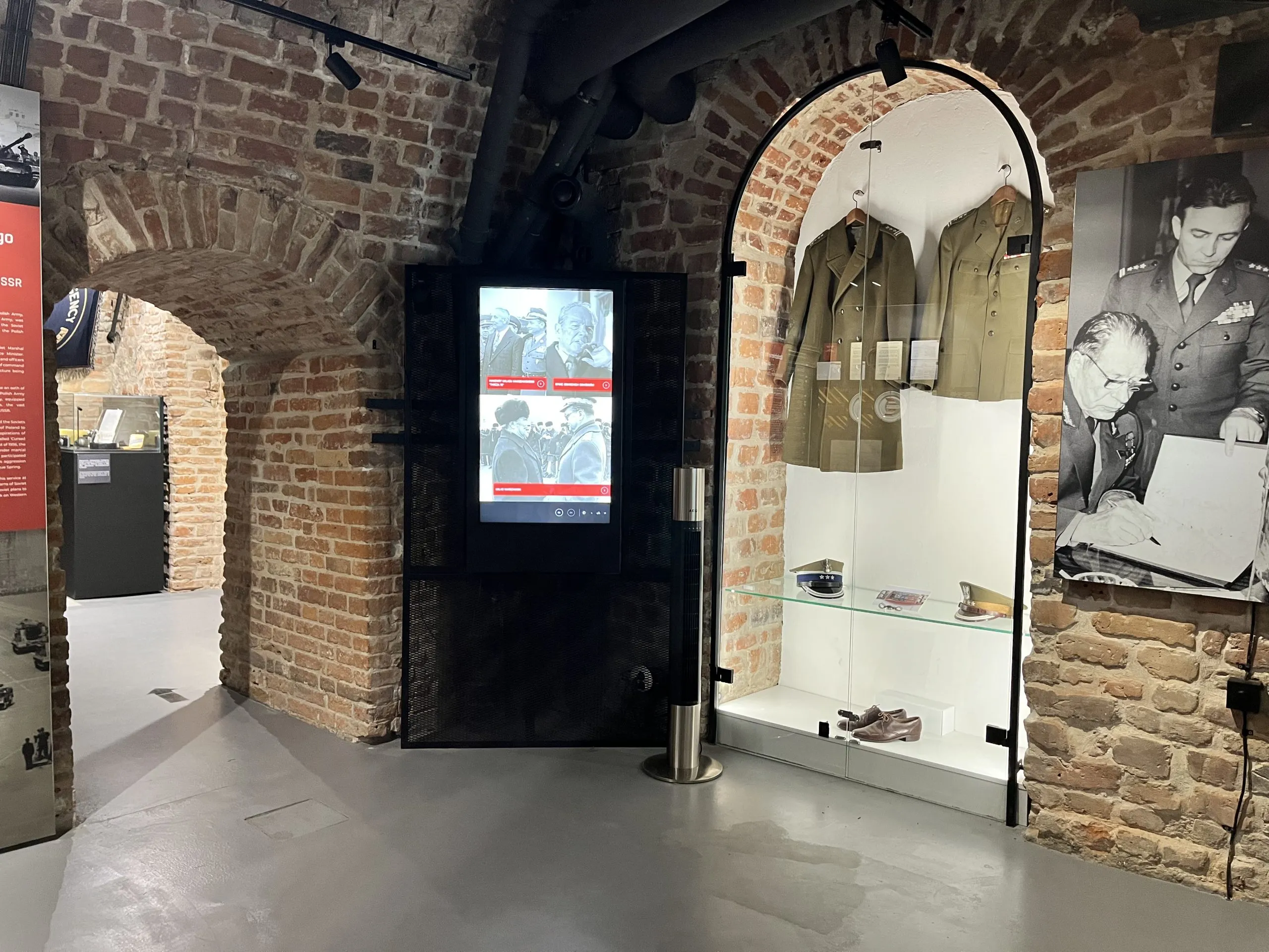 arco de ladrillo en un museo con vitrina y pantalla digital
