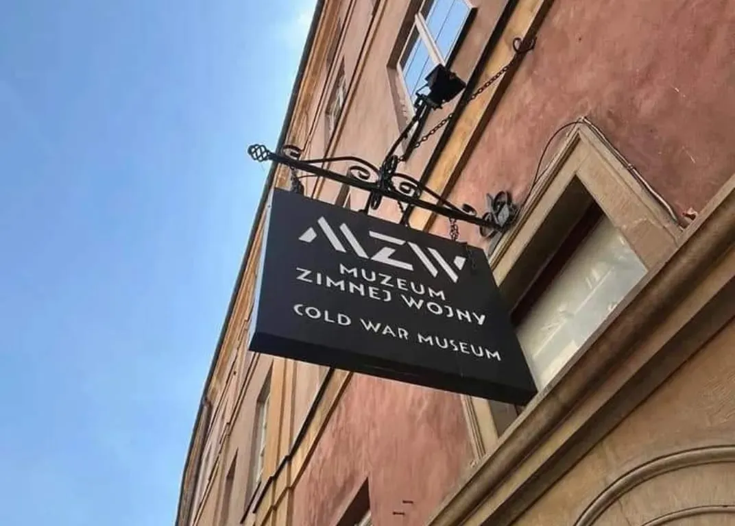 cartel negro colgante con texto blanco 'MZiW MUZEUM ZIMNEJ WOJNY COLD WAR MUSEUM' en la fachada de un edificio