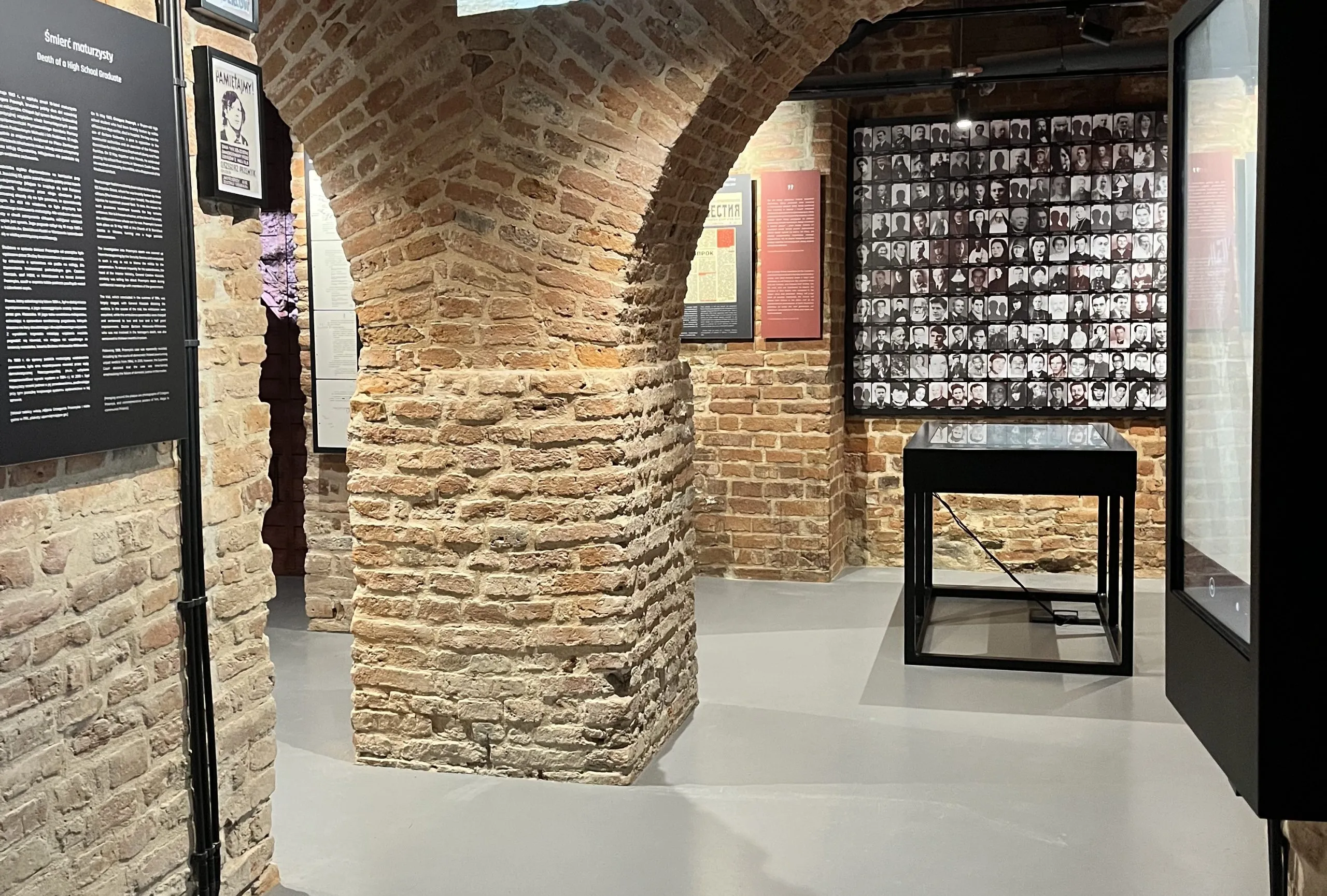 Interieur van het Museum van de Koude Oorlog met bakstenen bogen, informatiepanelen en een muur met foto's