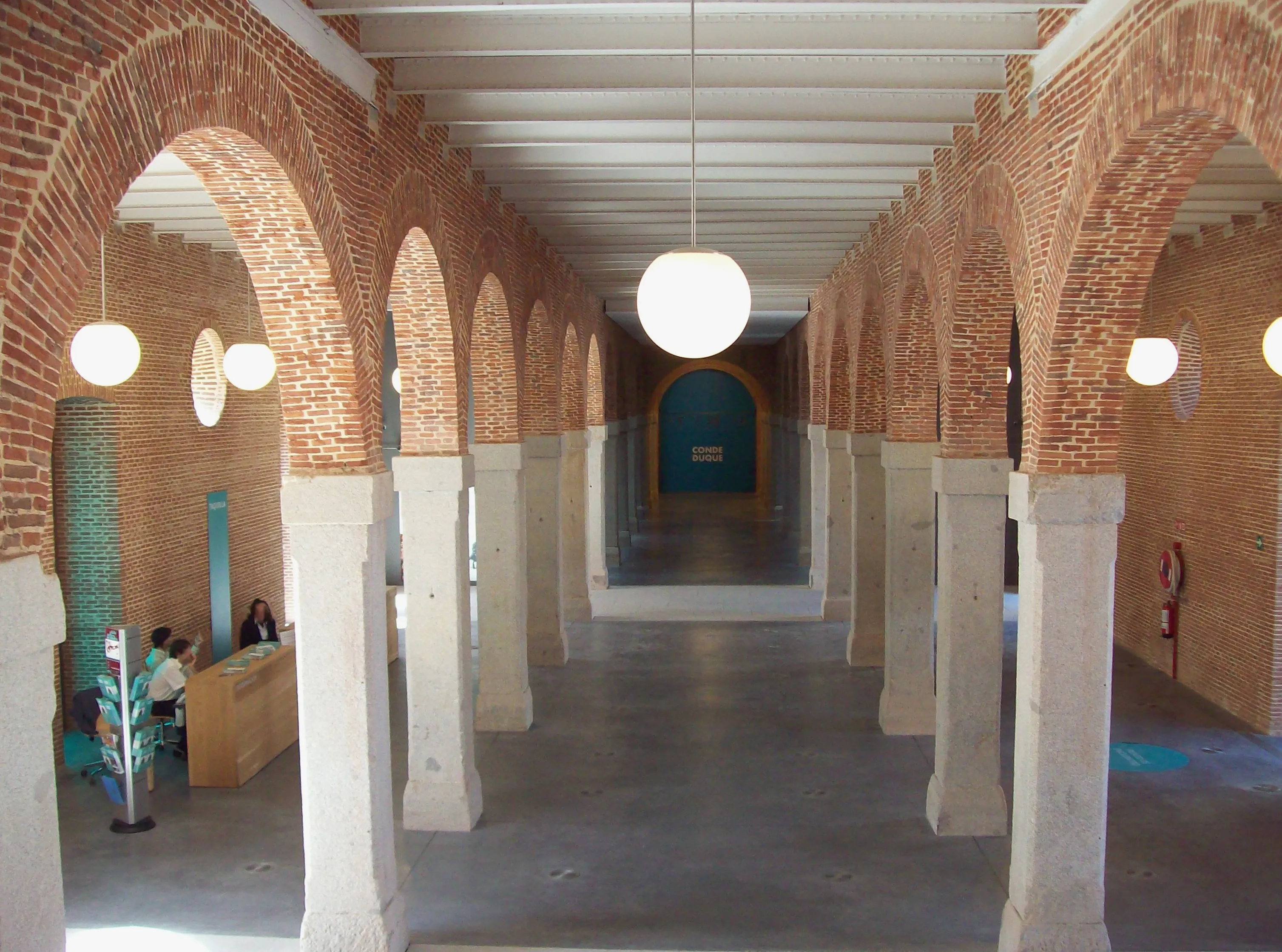 Pasillo con arcos de ladrillo y columnas blancas en el interior de un museo