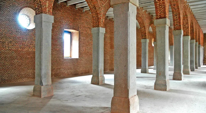 Interior de un gran salón con paredes de ladrillo, bóvedas de cañón y columnas de hormigón