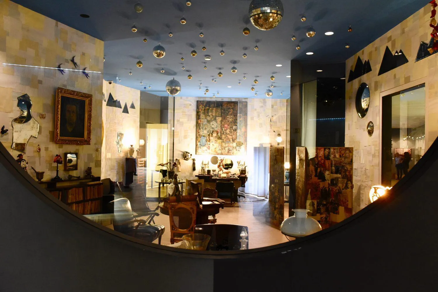 Interior de una galería de museo con techo azul, esferas reflectantes y varias obras de arte expuestas
