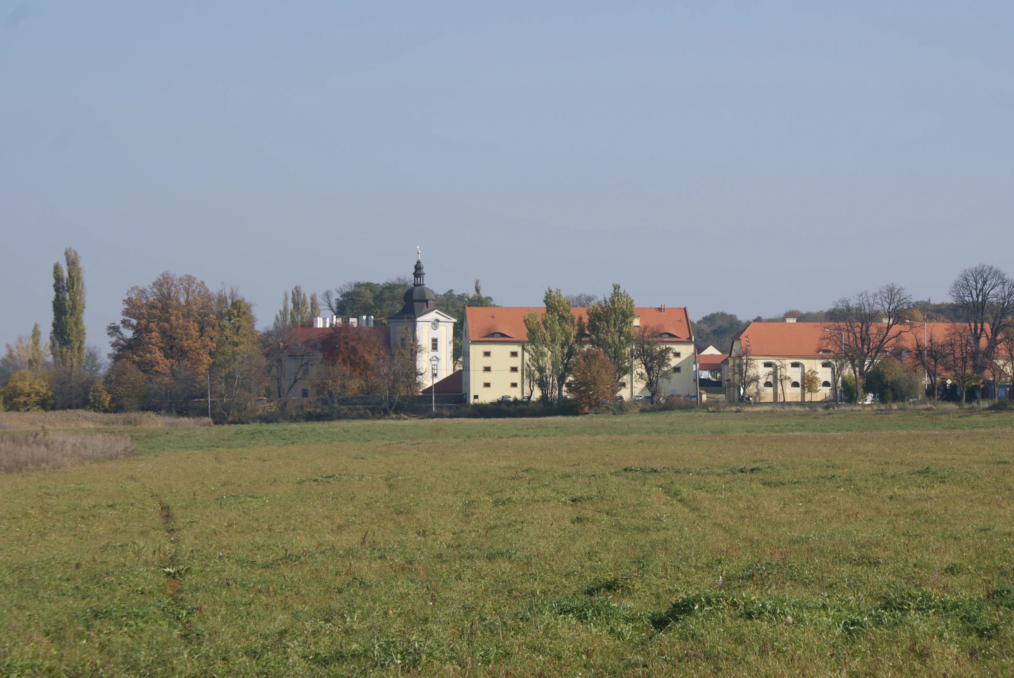 Kasteel Ctěnice met oranjedakige gebouwen en een centrale toren, omgeven door bomen en een grasveld