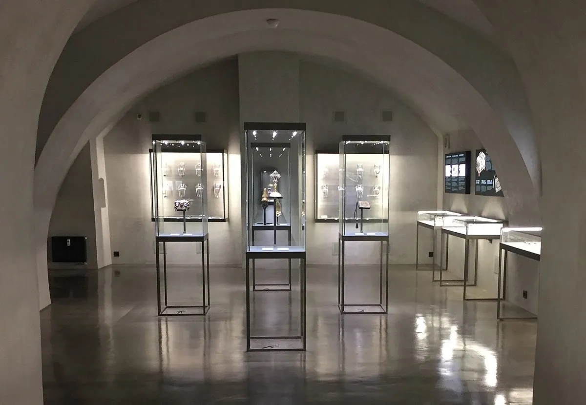Interior of a museum gallery with arched ceilings, glass display cases, and reflective floors