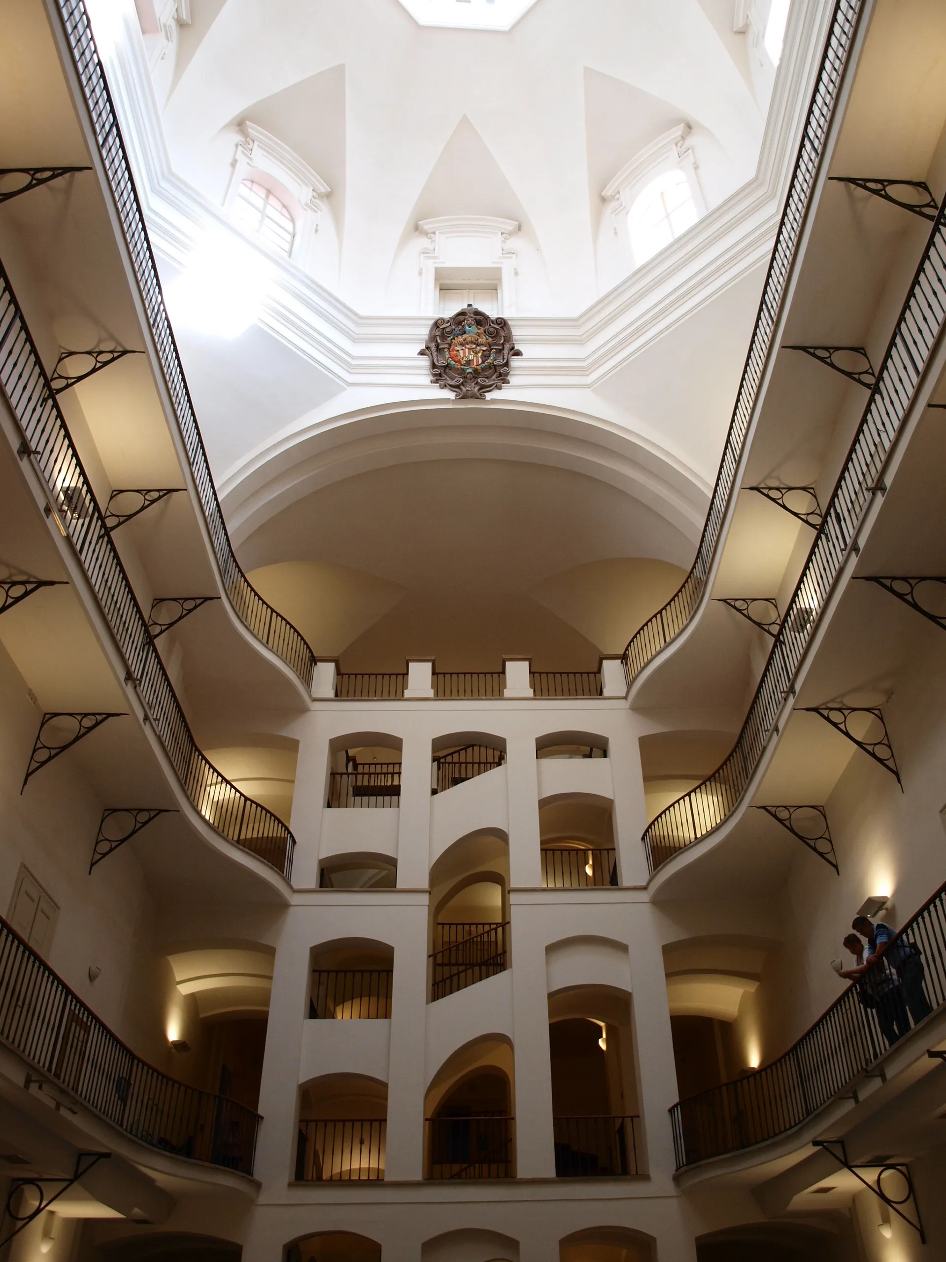 Interieur van een meerlaags atrium met boogvormige loopbruggen en een hoog plafond in een gebouw in barokstijl