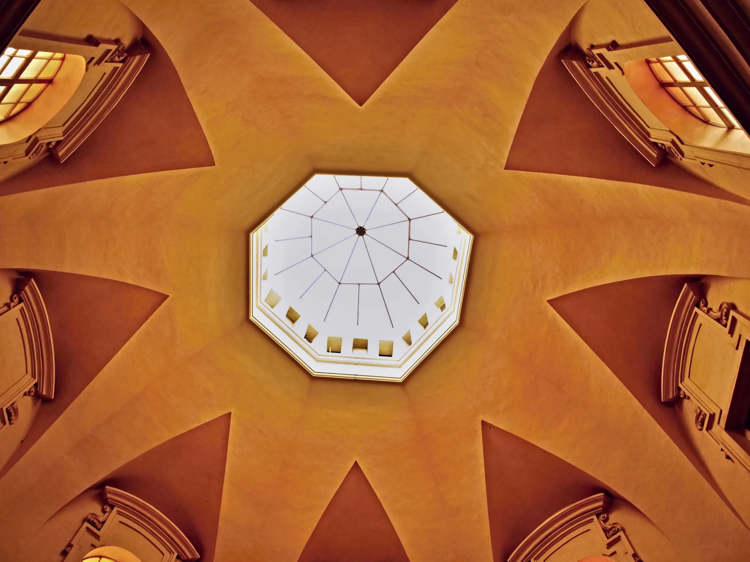 achthoekige dakkoepel in een gewelfd plafond met warme gele tinten en geometrische patronen