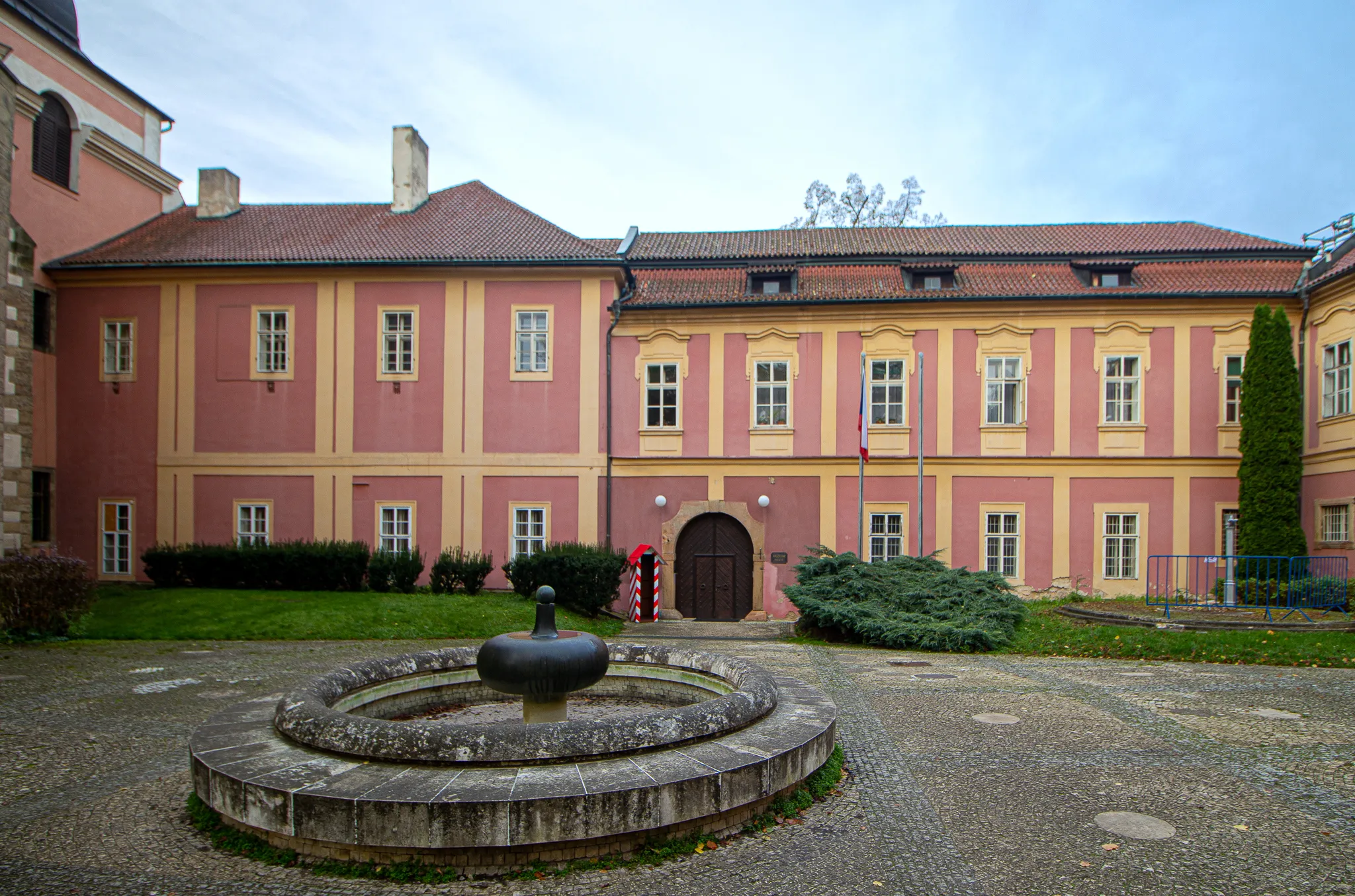Pink and yellow building with a central courtyard featuring a stone fountain and a red fire hydrant