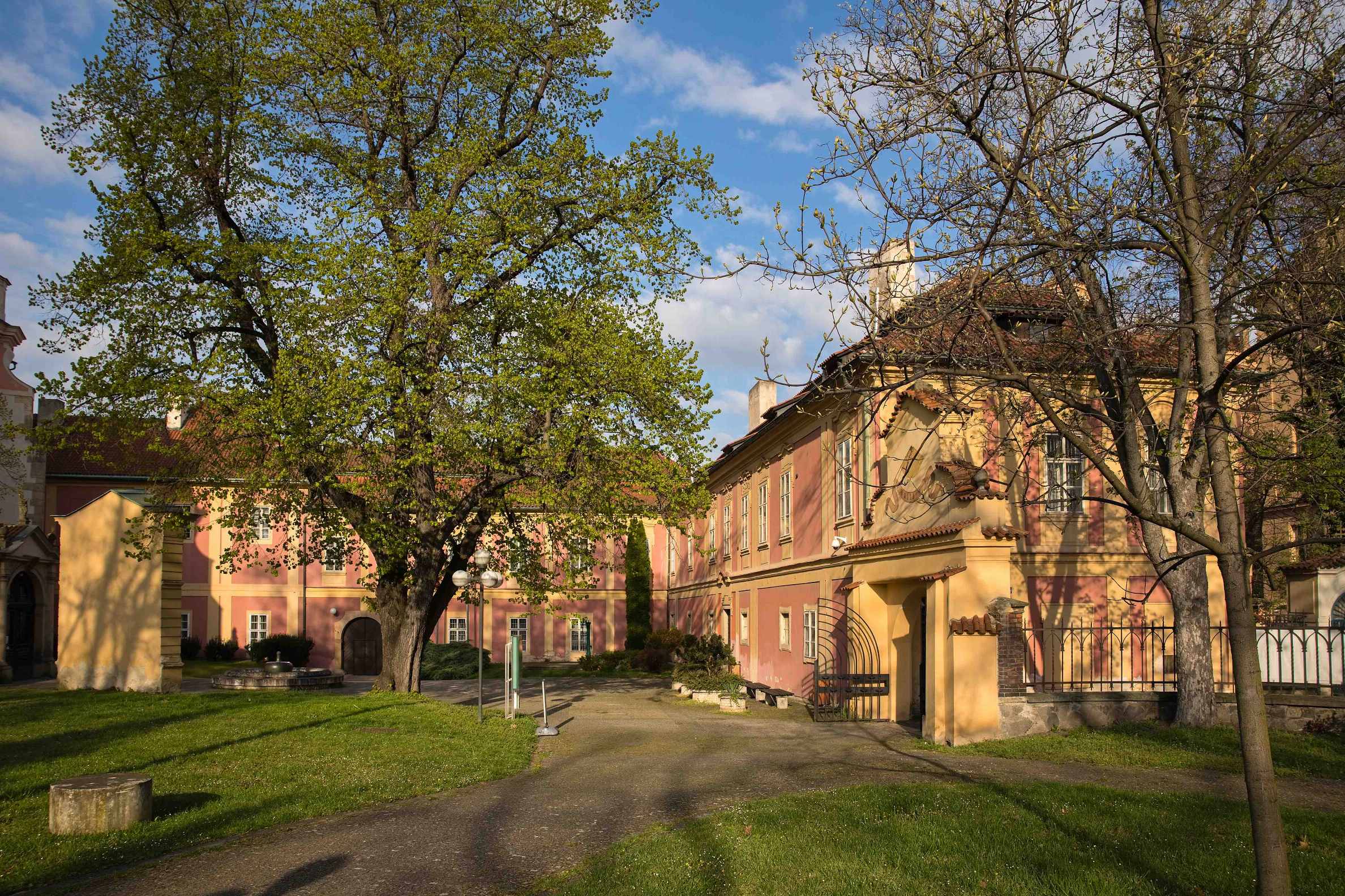 courtyard of a historic building with a gravel path, green lawns, and trees