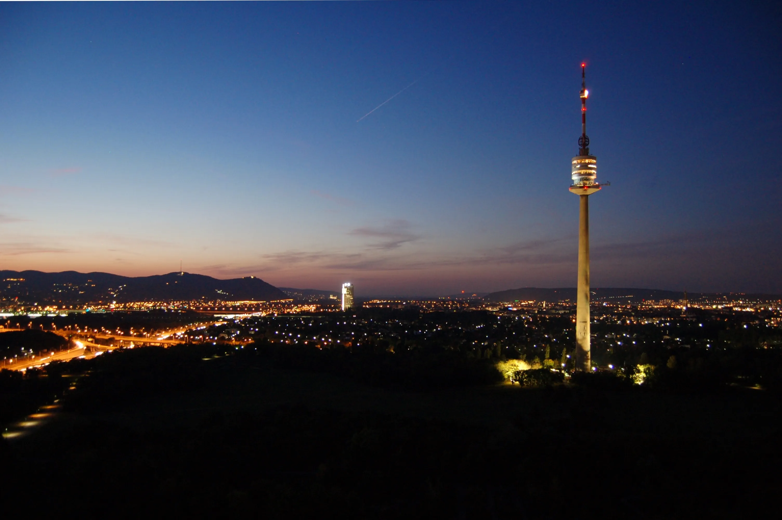 Danube Tower lit at night with city lights in the background
