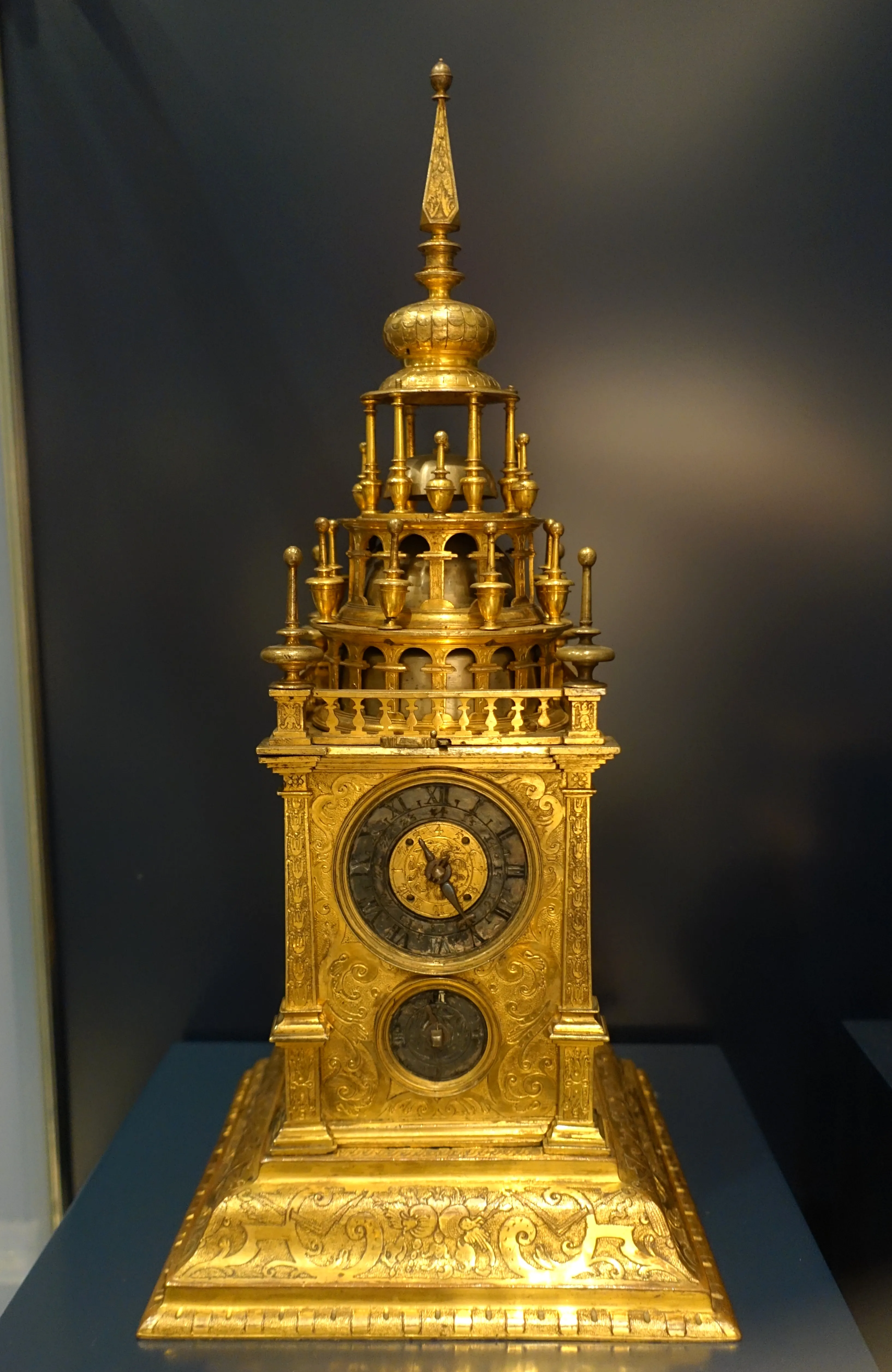 Un ornamentado reloj dorado con intrincadas tallas y una aguja en exhibición