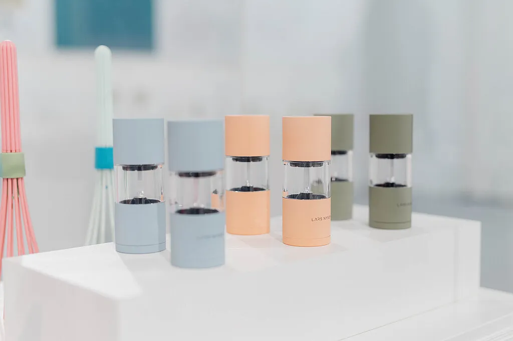 Una fila de productos de diseño moderno en colores pastel sobre un expositor blanco