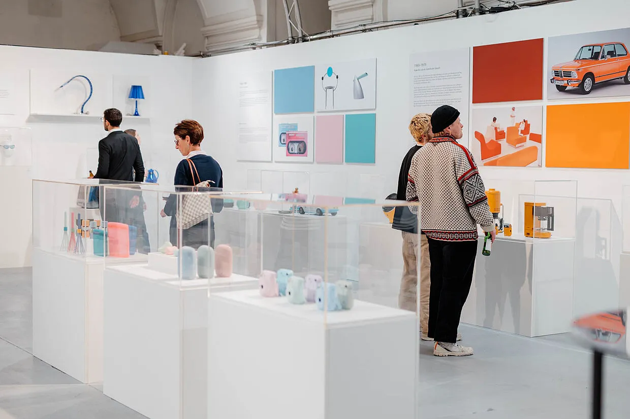 Personas viendo productos de diseño en vitrinas en una exposición en designforum Wien