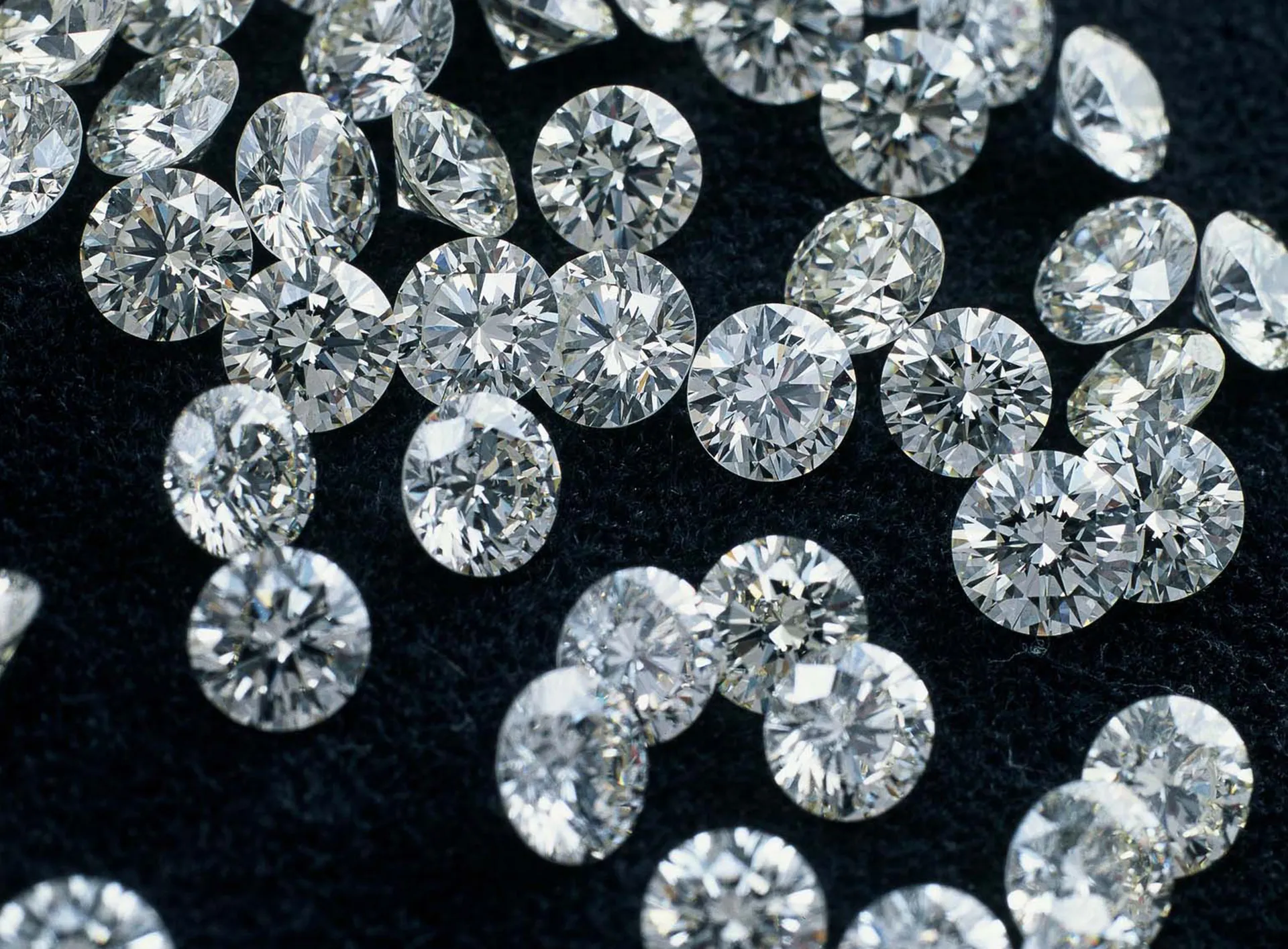 Diamantes sueltos de talla brillante redonda esparcidos sobre una superficie de terciopelo negro