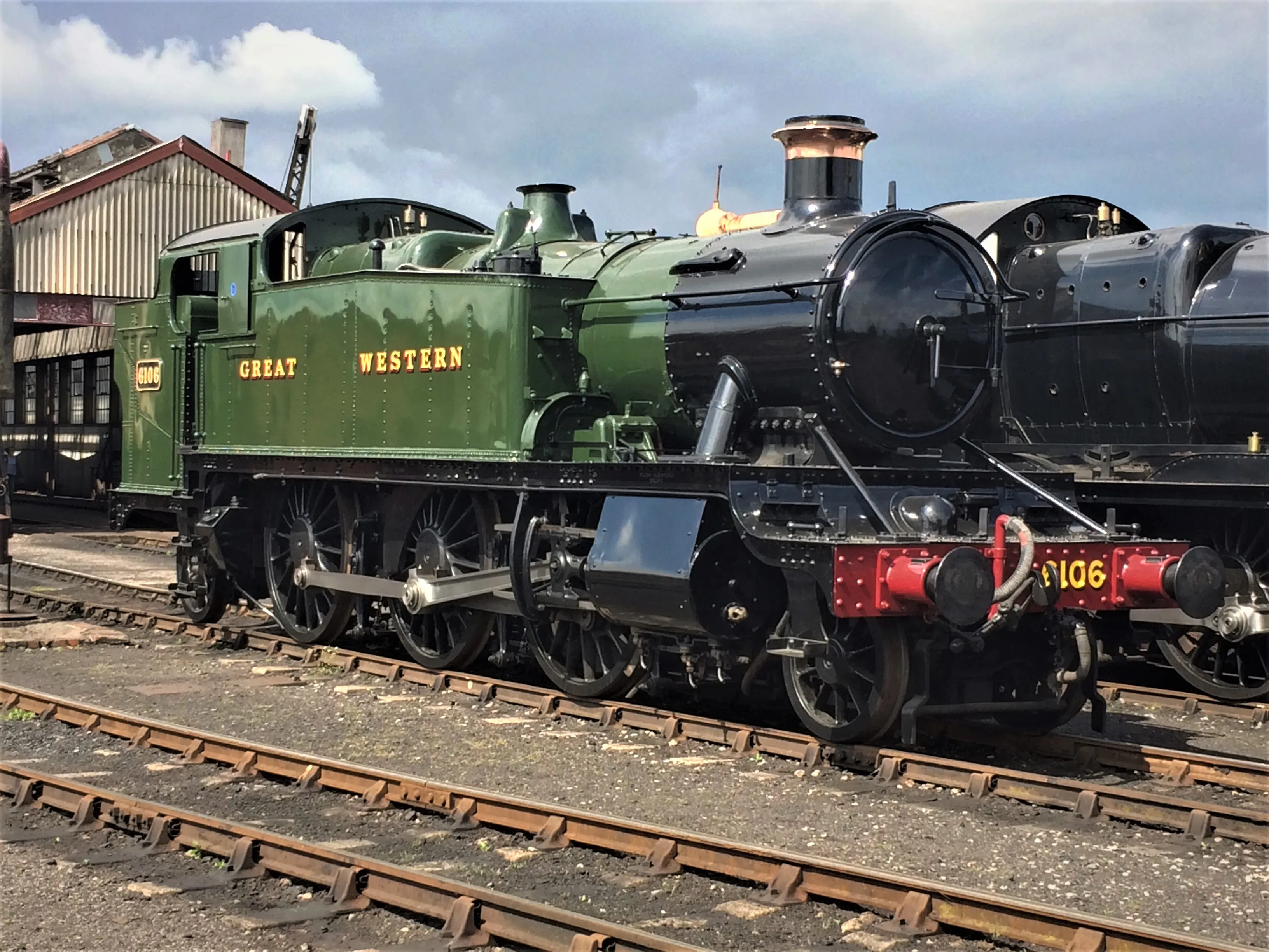 Zielona lokomotywa parowa Great Western Railway numer 6106 na torach kolejowych, z inną lokomotywą w tle.