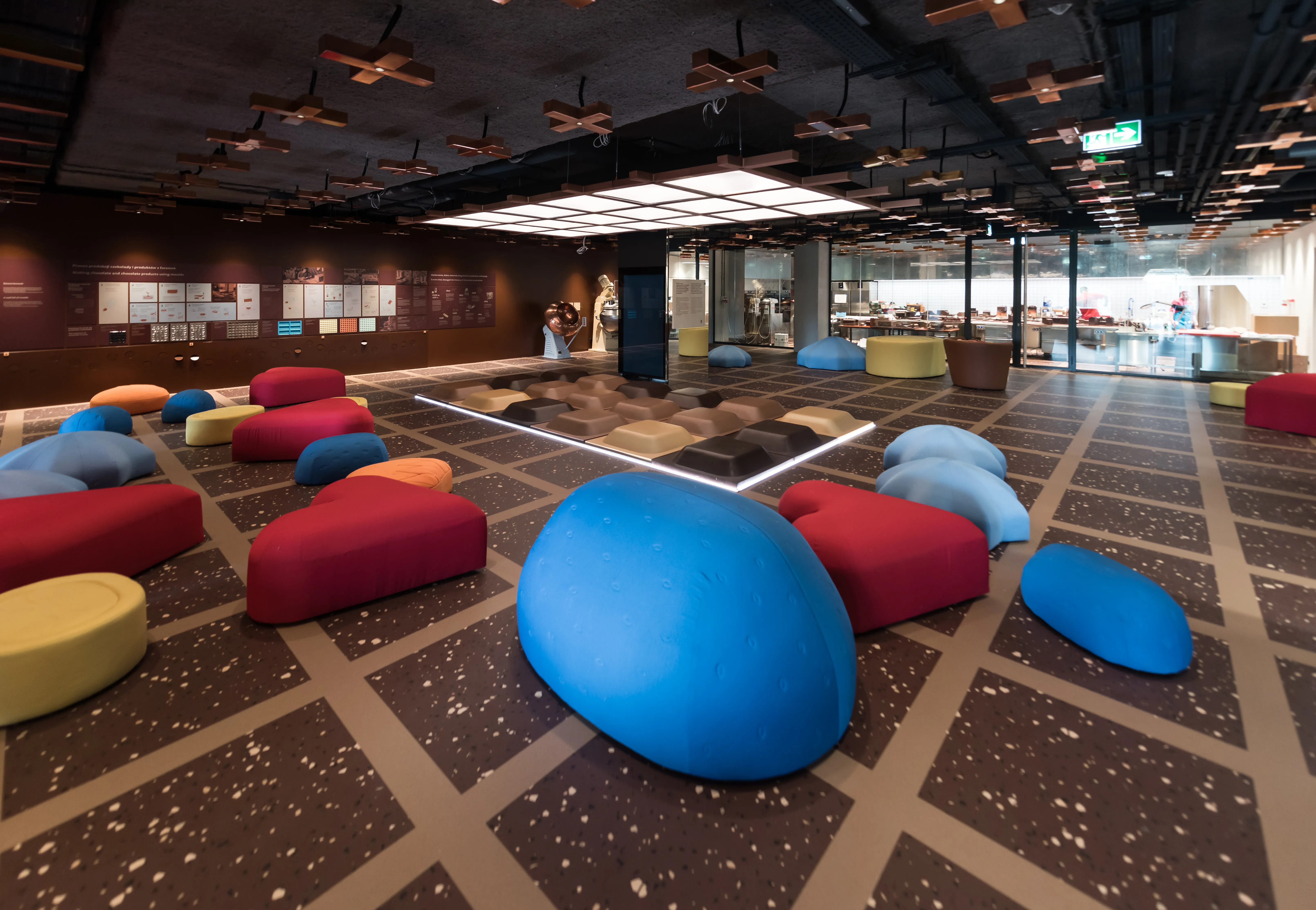 Colorful beanbag seating in red, blue, and yellow on a patterned floor inside a modern interior space