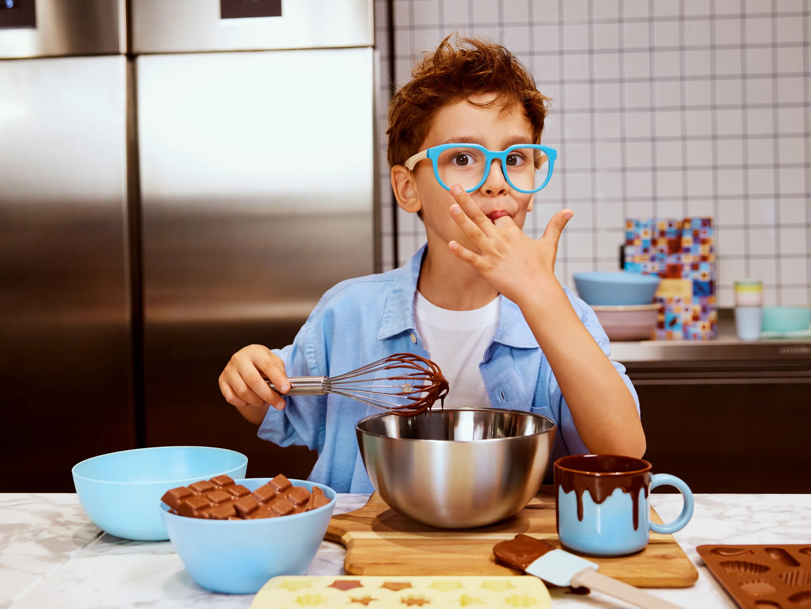 a young boy in a kitchen with chocolate-making supplies