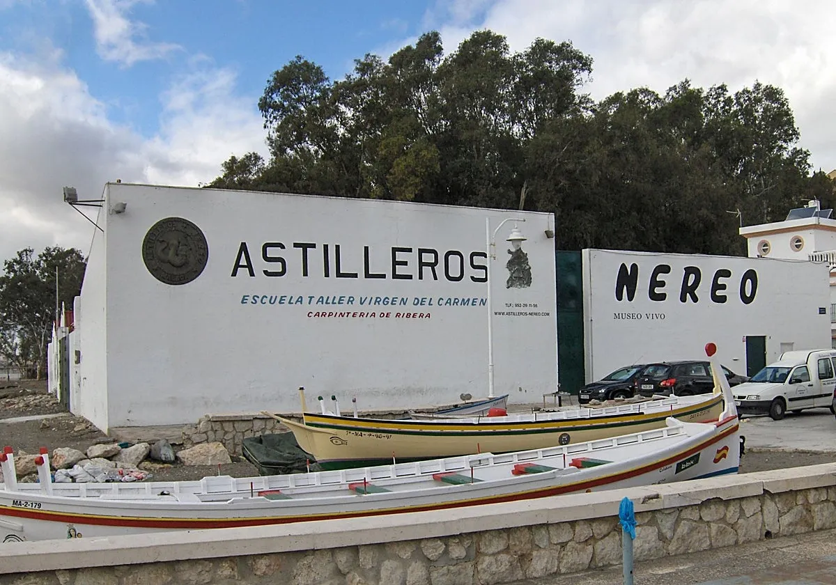 Edificio blanco con carteles de ASTILLEROS NEREO y barcos de madera tradicionales expuestos fuera del astillero