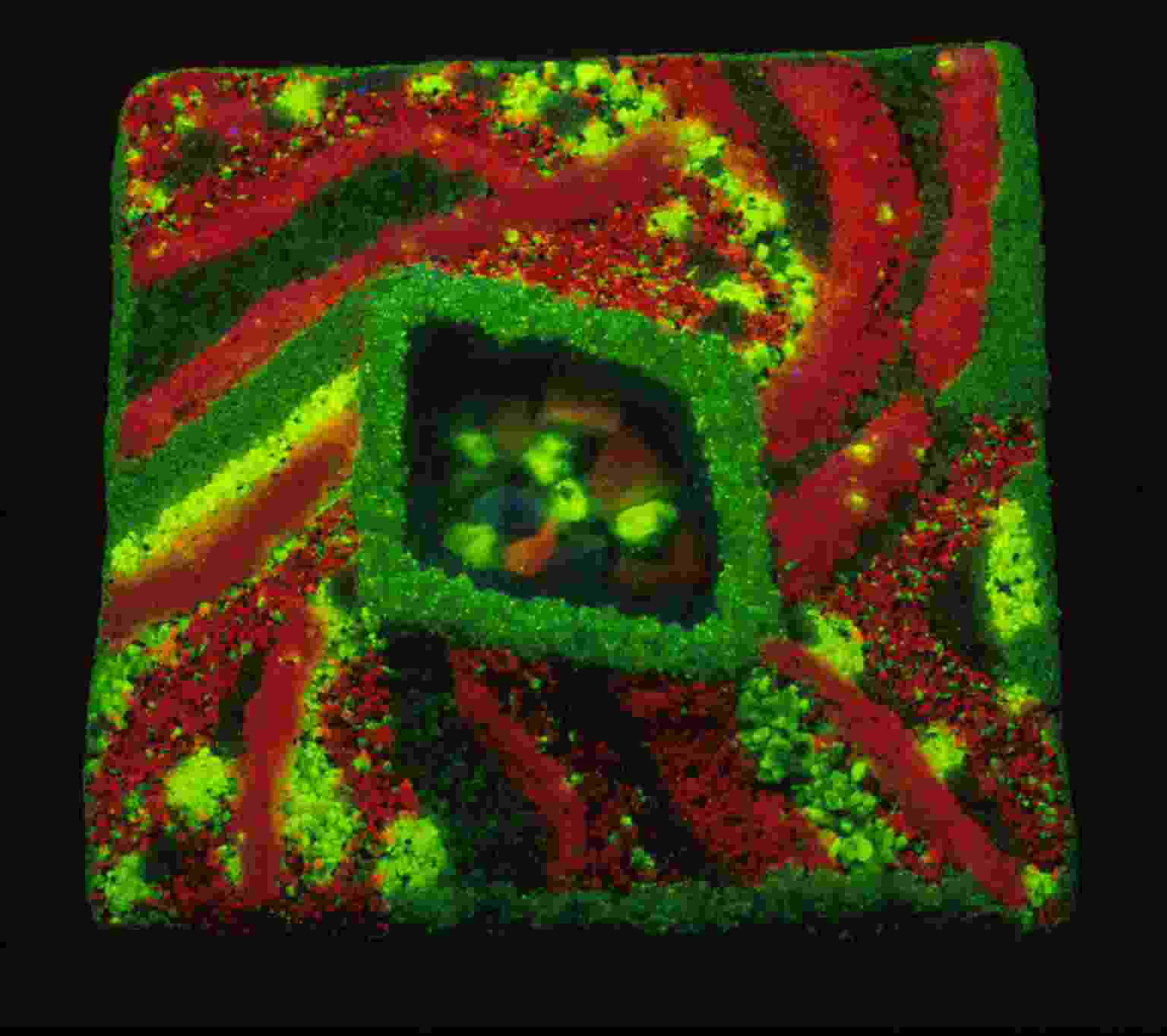Patrones minerales fluorescentes de vibrantes rojos y verdes forman diseños abstractos arremolinados alrededor de una sección central brillante