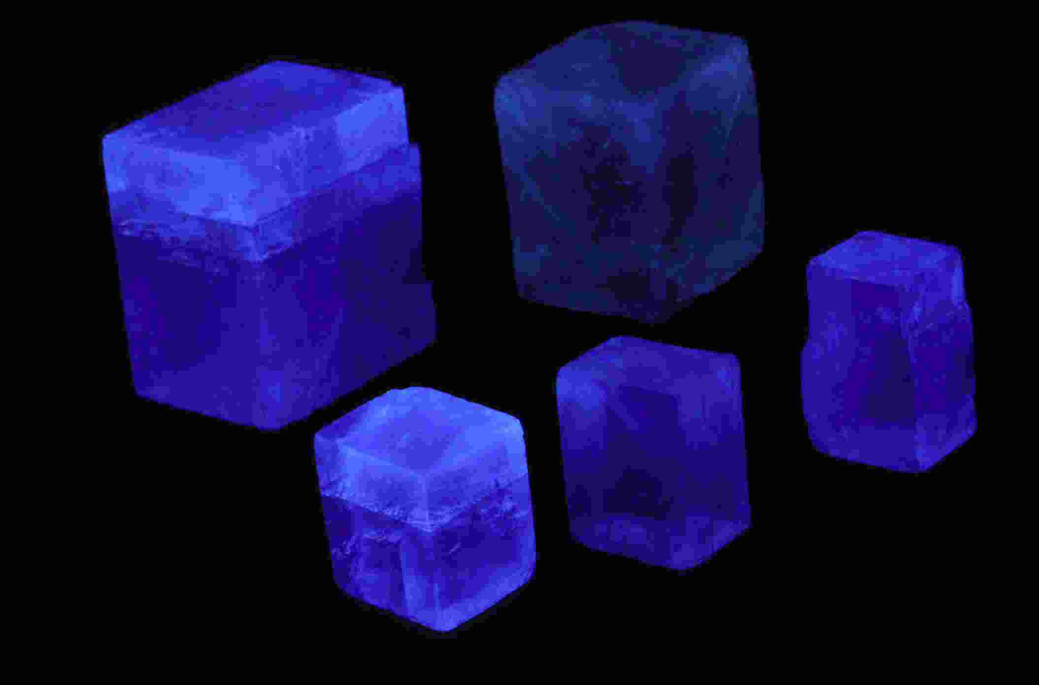 Five glowing blue fluorescent cubes of varying sizes arranged against a black background