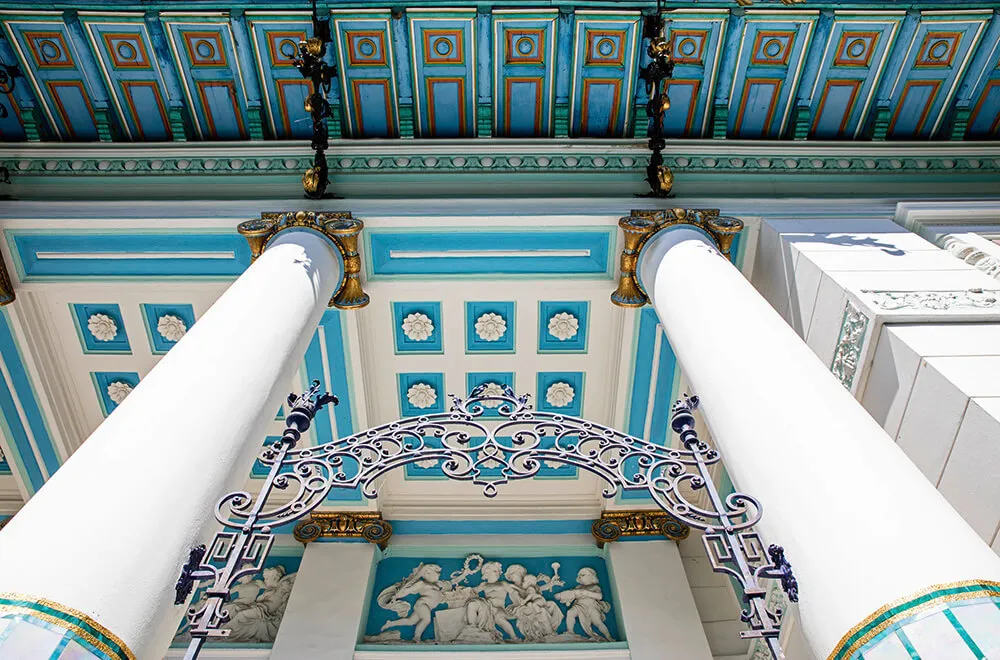 Ozdobny niebiesko-biały sufit z dekoracyjnymi kafelkami i białymi kolumnami w Muzeum Ernsta Fuchsa