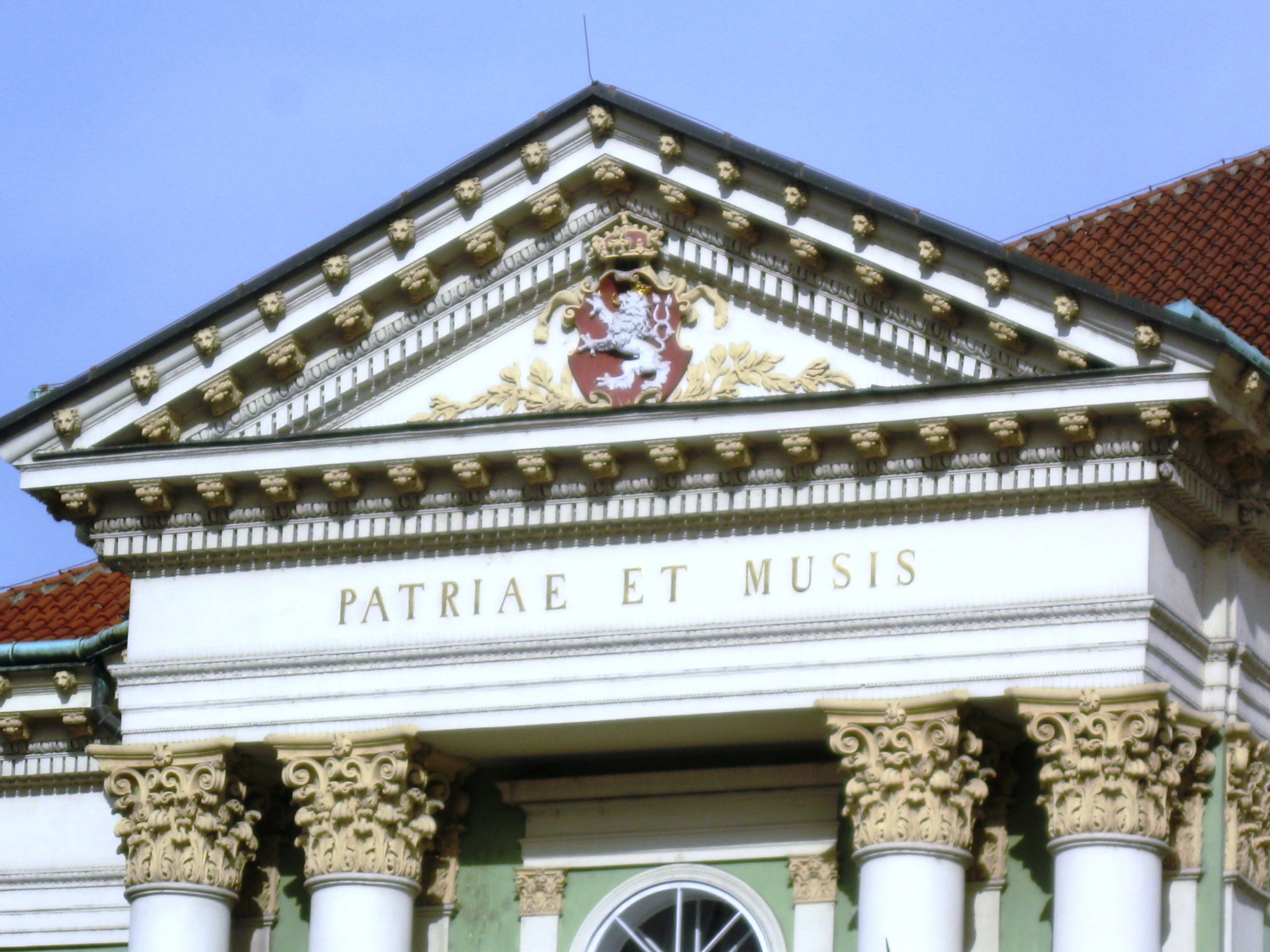 De gevel van het Estates Theatre met sierlijke zuilen, een fronton en het opschrift 'PATRIAE ET MUSIS'