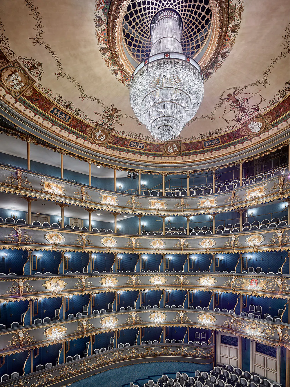 Interior of the Estates Theatre with multiple levels of balconies, a large chandelier, and decorative ceiling frescoes