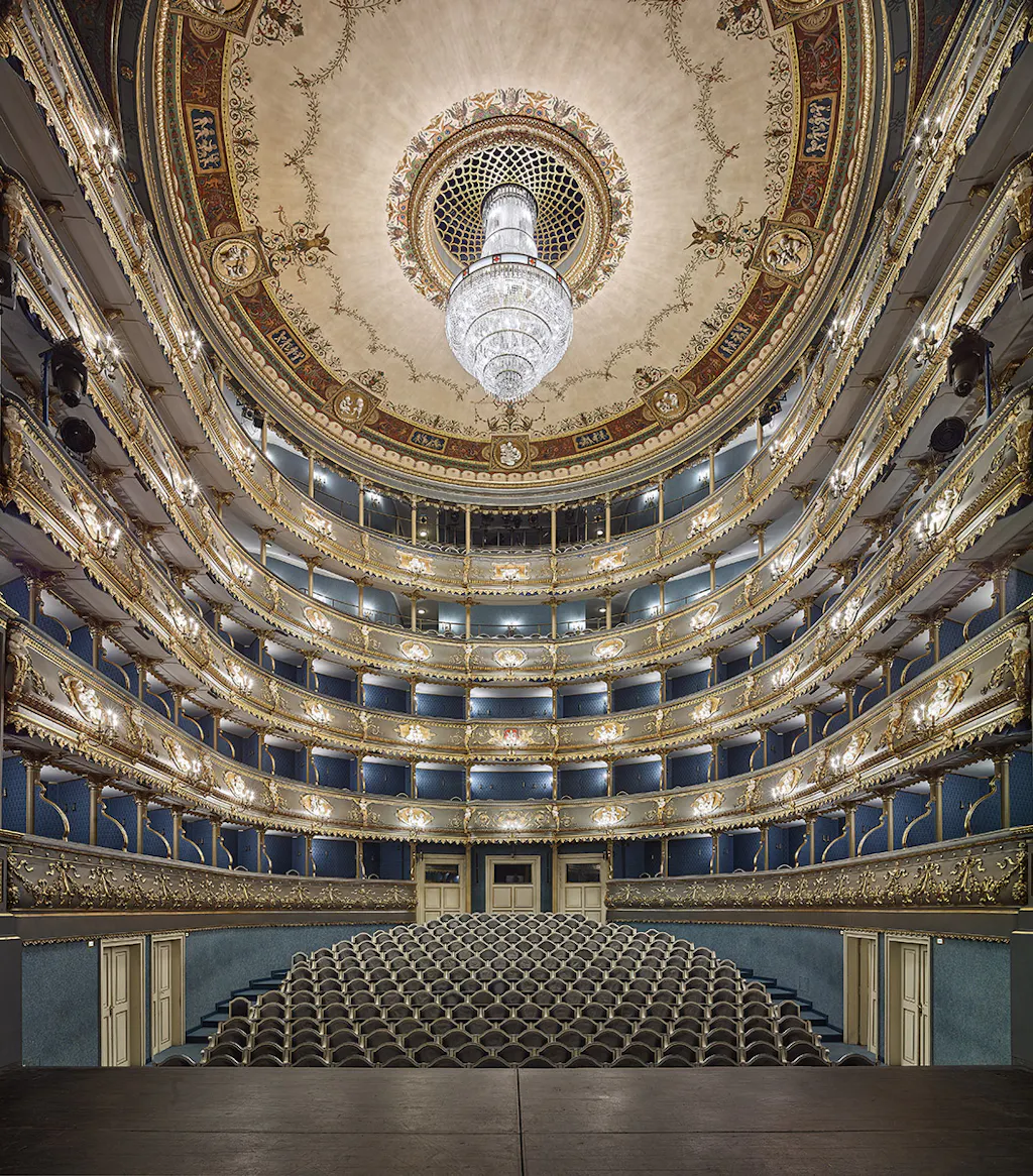 Interior of the Estates Theatre with ornate balconies, a grand chandelier, and a decorated ceiling