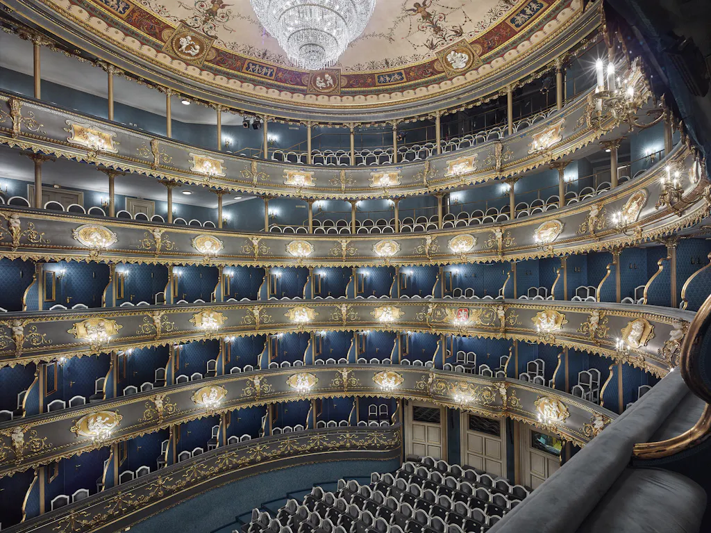 Ornate interior of the Estates Theatre with tiered balconies, gilded details, and a central chandelier