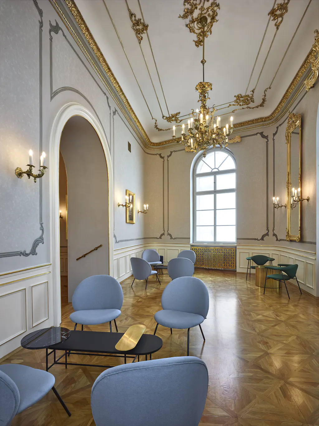Interieur van het Estates Theatre met sierlijk plafond, kroonluchter en blauwe stoelen