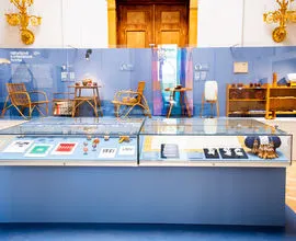 Vitrina de cristal con artefactos y artesanías tradicionales checas, rodeada de muebles de madera y paredes azules en una galería de museo