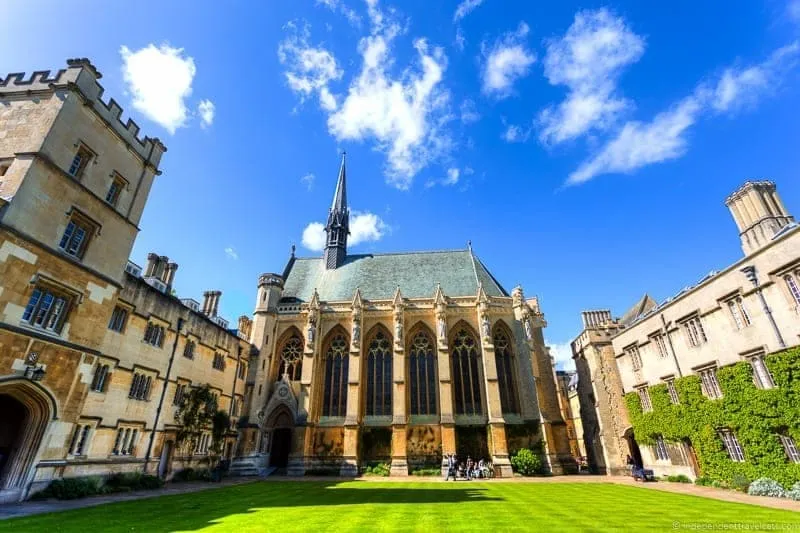 Neogotycka kaplica z wysoką iglicą przy Exeter College, otoczona kamiennymi budynkami i zielonym dziedzińcem pod błękitnym niebem z chmurami