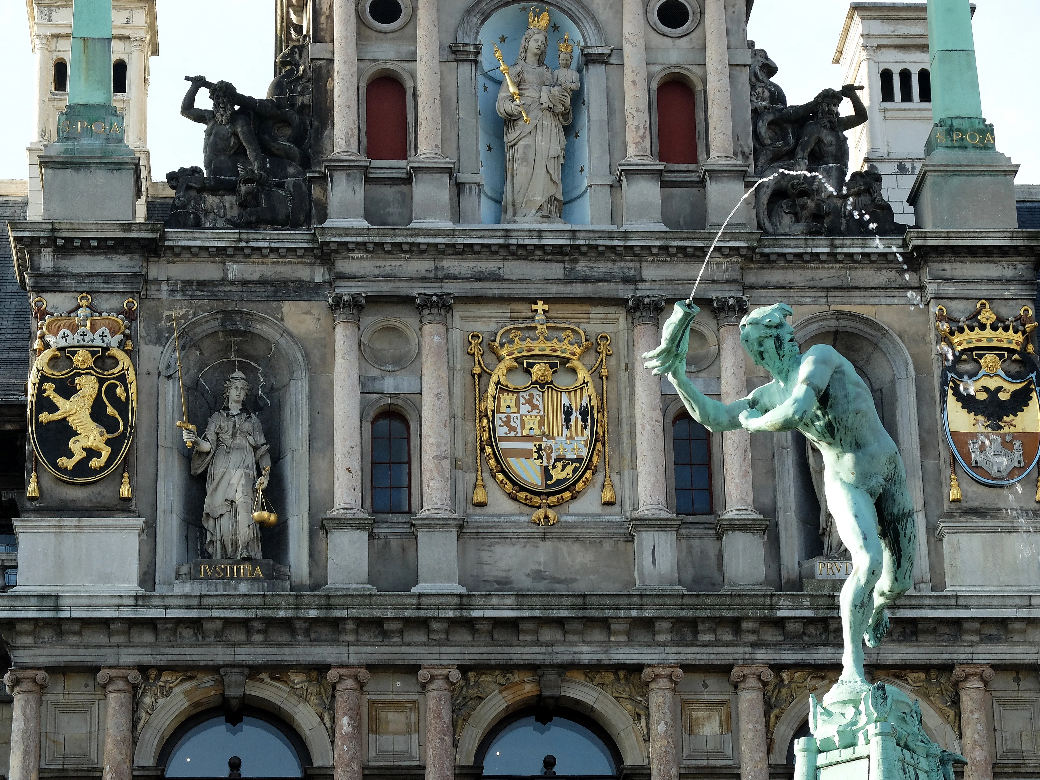Fachada del Ayuntamiento de Amberes con ornamentos en piedra, escudos de armas, estatuas en nichos y la estatua de la fuente de Brabo en primer plano