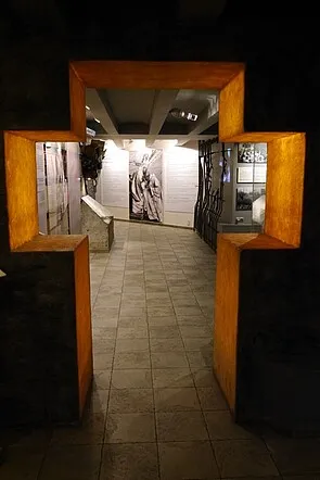 marco de madera en forma de cruz que conduce a un pasillo de museo con una fotografía grande en la pared