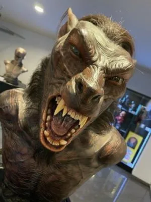Un primer plano de un disfraz de hombre lobo con dientes afilados y ojos brillantes expuesto en un museo