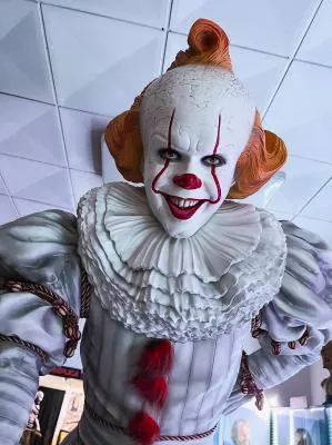 Figura de tamaño real del payaso Pennywise con maquillaje blanco, nariz roja y pelo naranja