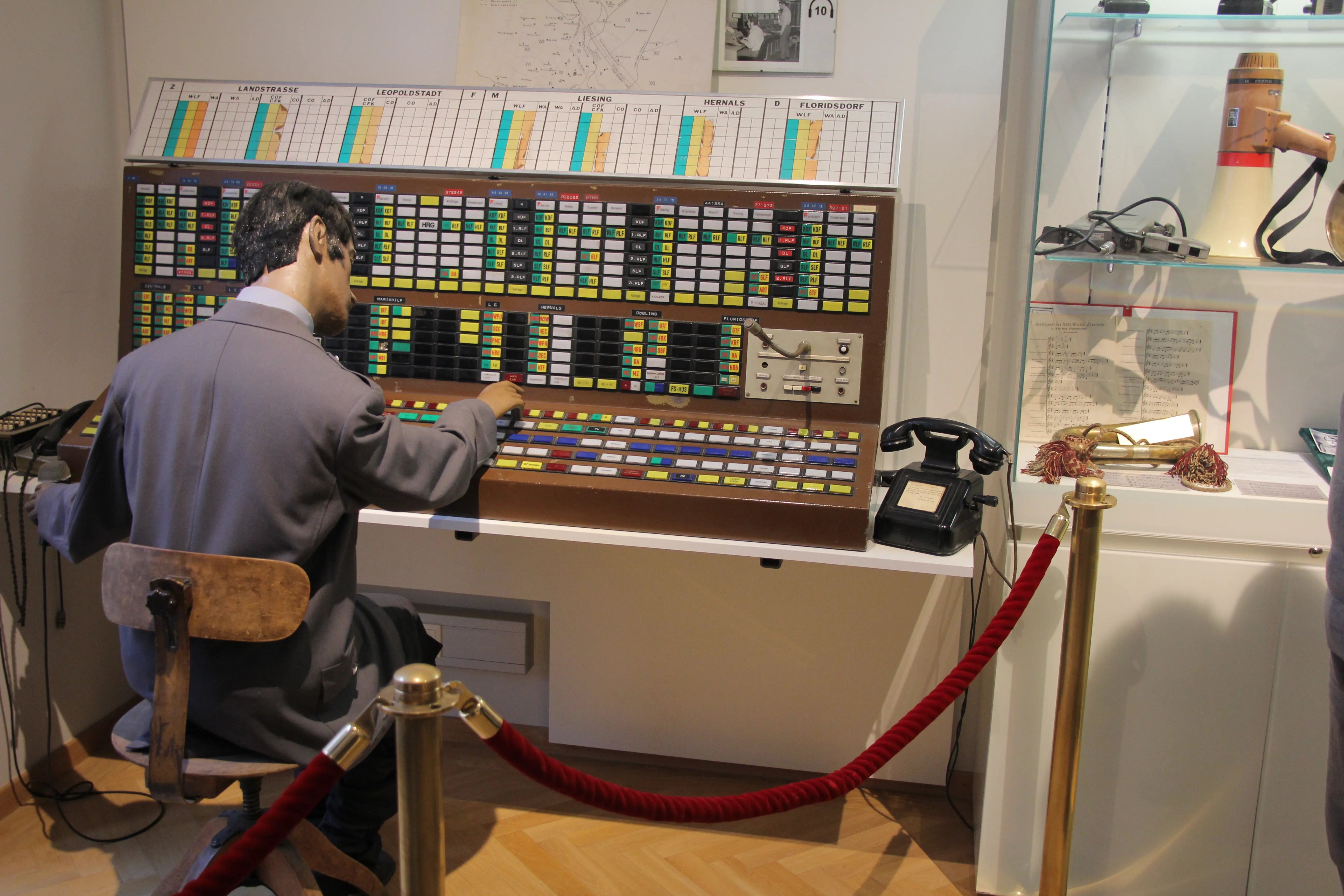 Manekin obsługujący zabytkowy panel sterowania z przyciskami i przełącznikami w Muzeum Straży Pożarnej w Wiedniu