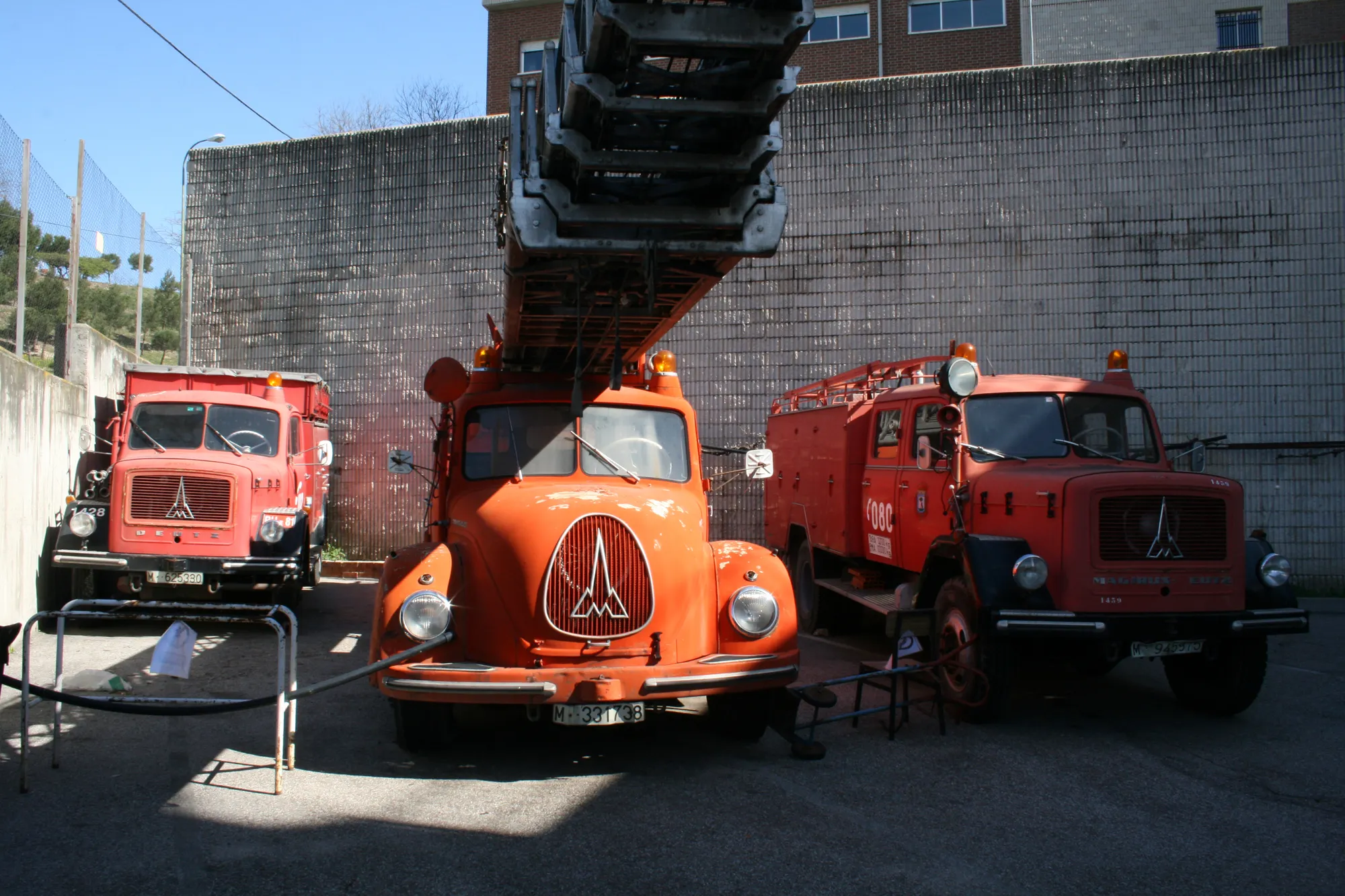 Tres camiones de bomberos rojos y naranjas vintage estacionados afuera de un edificio