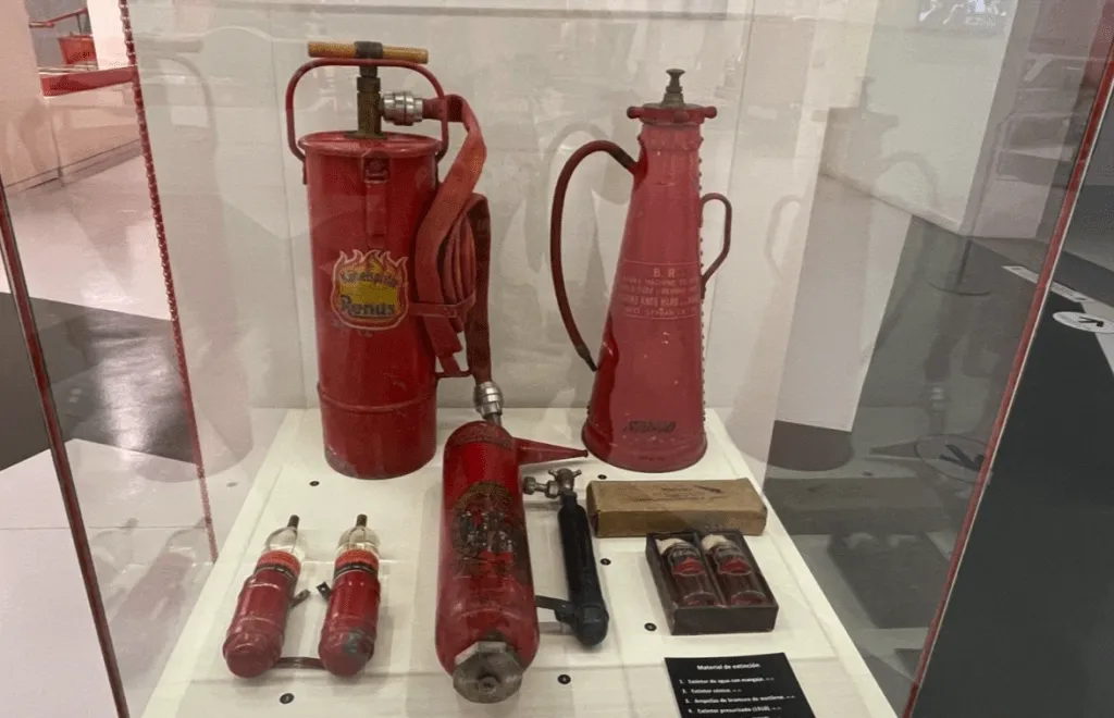 Extintores rojos vintage y herramientas de lucha contra incendios expuestos en una vitrina de cristal