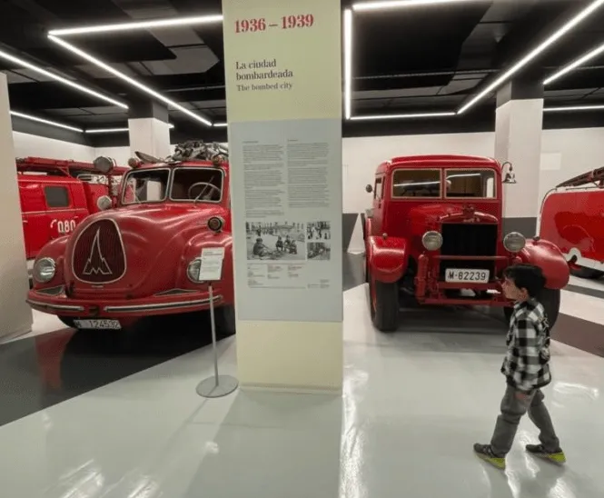 Camiones de bomberos rojos vintage expuestos en una sala de museo con señalización informativa