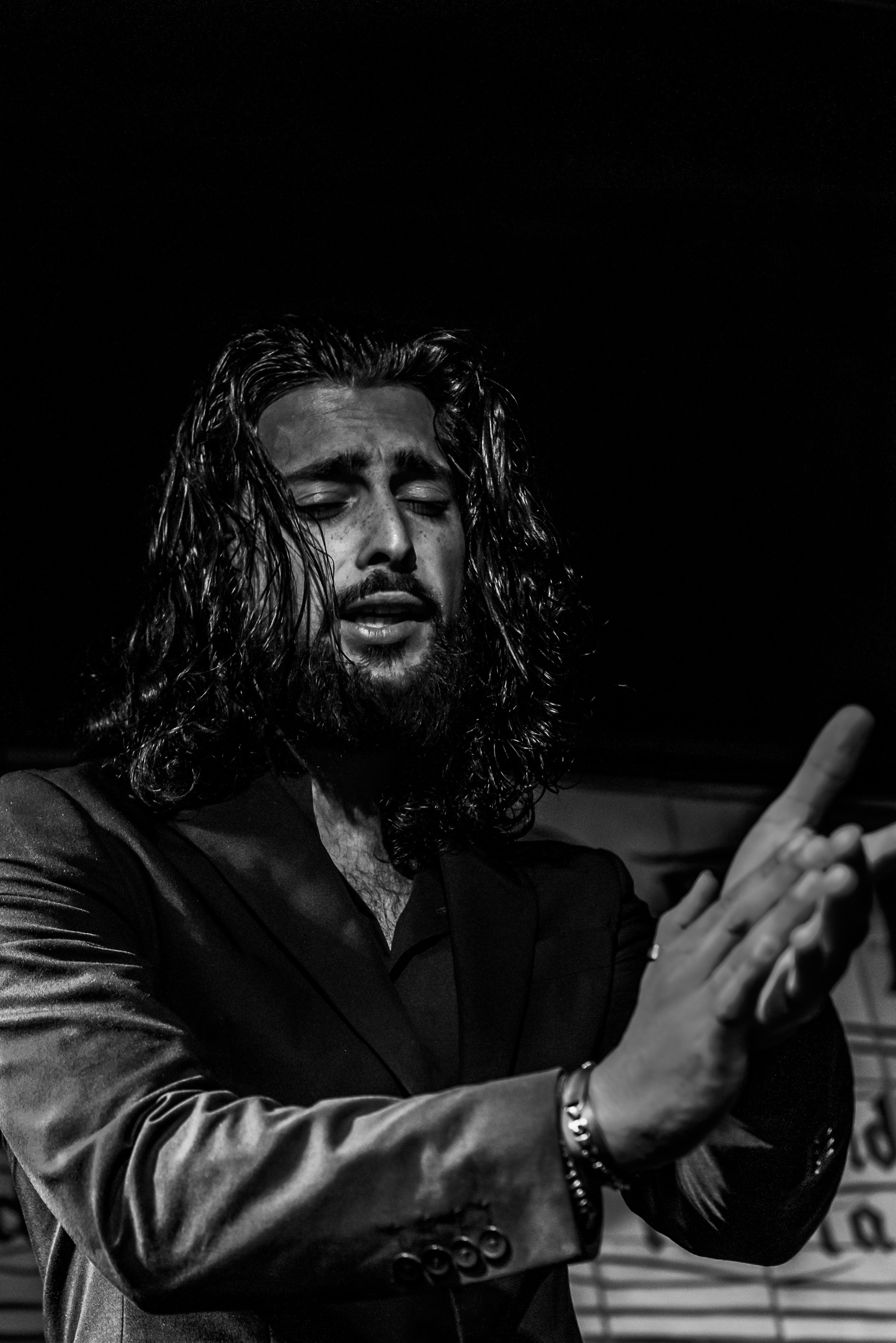 Un hombre con pelo largo y barba aplaudiendo durante una actuación de flamenco