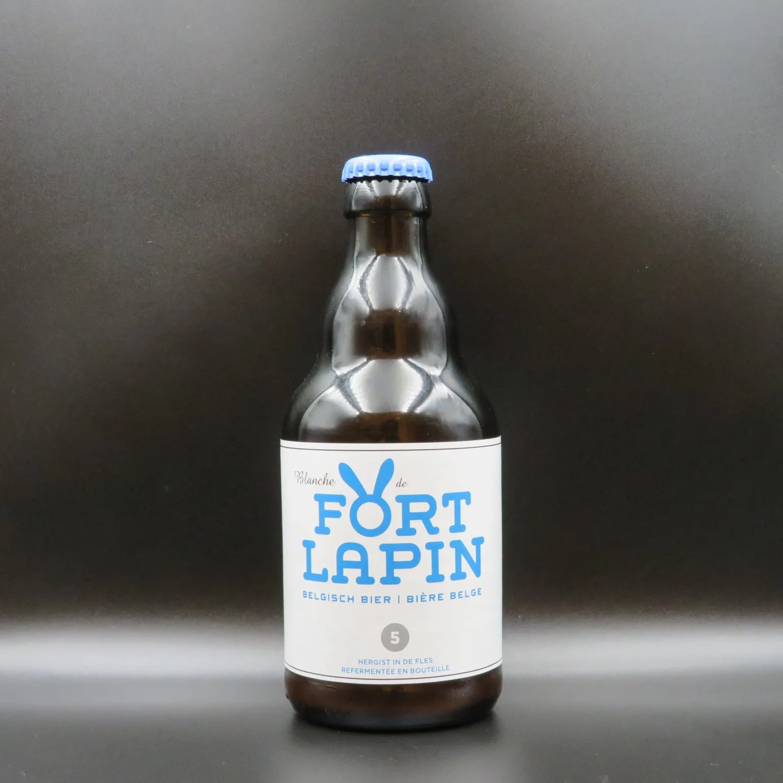 Brązowa szklana butelka piwa z niebieskim kapslem i białą etykietą z napisem 'FORT LAPIN', niebieskim logo królika oraz tekstem 'BELGISCH BIER - BIÈRE BELGE'