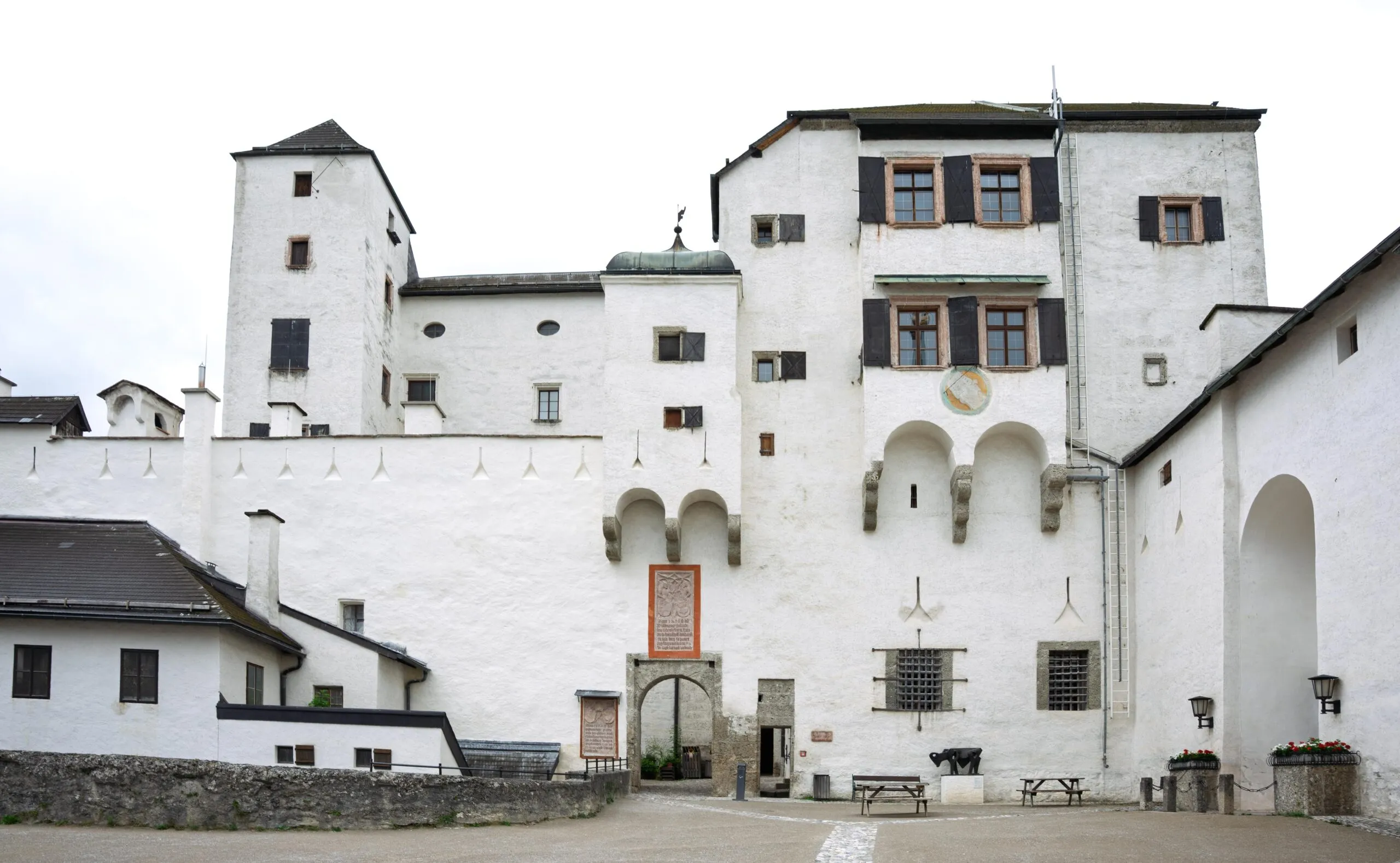 Wybielone mury obronne z wieżami, łukowymi bramami i okiennicami w twierdzy Hohensalzburg