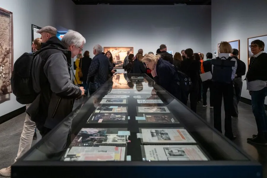 Mensen bekijken foto's in een glazen vitrine in een museumgalerij