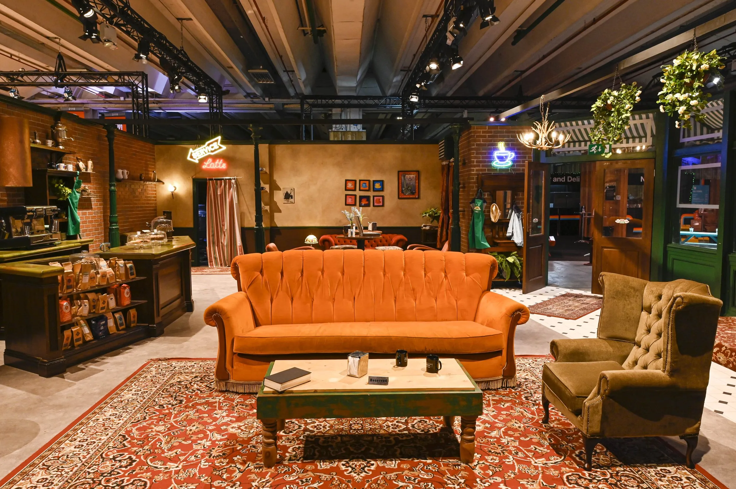 Oranje bank in een nagebouwde Central Perk-set met een salontafel en een vloerkleed met patroon