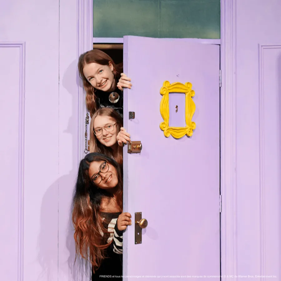 Three people peeking through a purple door with a yellow picture frame